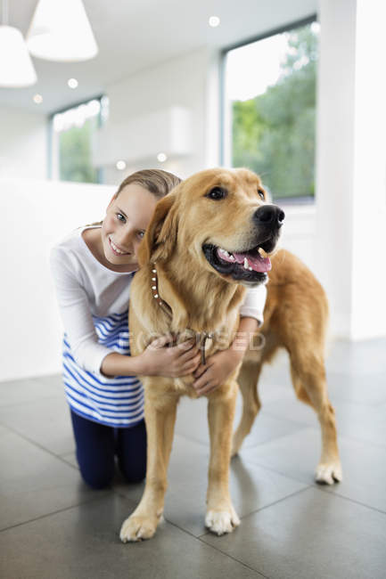 Girl hugging dog at modern home — Stock Photo