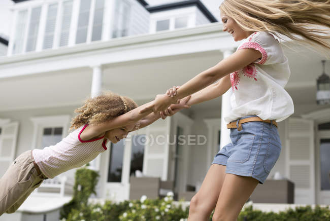 Mother and daughter playing outside house — Stock Photo