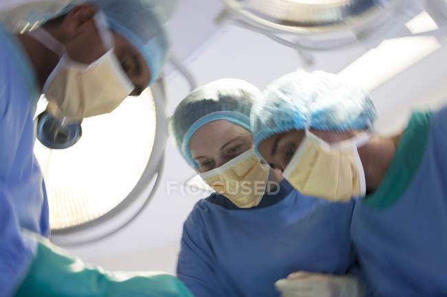 Cirurgiões dobrados sobre o paciente na sala de cirurgia — Fotografia de Stock
