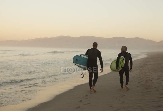 Старі серфери, що несуть дошки на пляжі — стокове фото