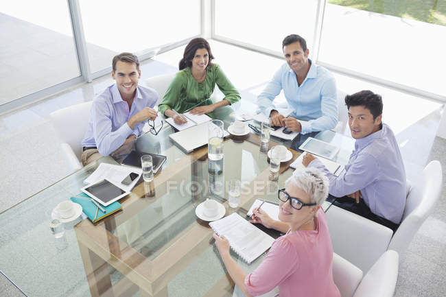 Деловые люди улыбаются на встрече в современном офисе — стоковое фото