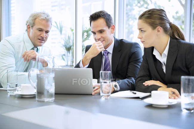 Pessoas de negócios compartilhando laptop em reunião no escritório moderno — Fotografia de Stock