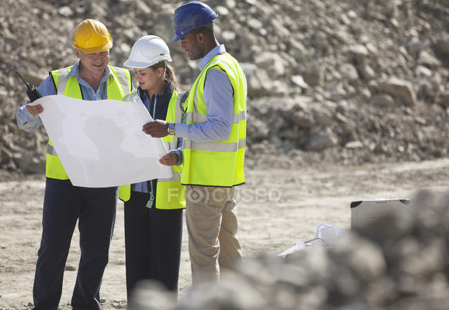 Business people reading blueprints in quarry — Stock Photo