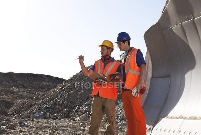 Workers talking by machinery in quarry — Stock Photo