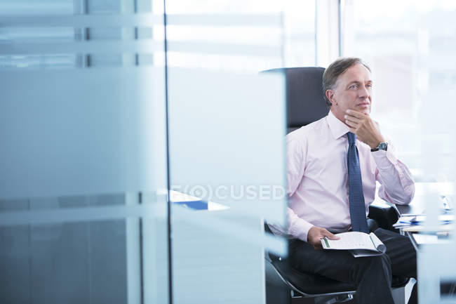 Geschäftsmann denkt am Schreibtisch im modernen Büro — Stockfoto