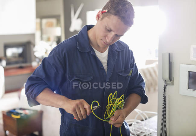 Hábil eletricista caucasiano cortando fios em casa — Fotografia de Stock