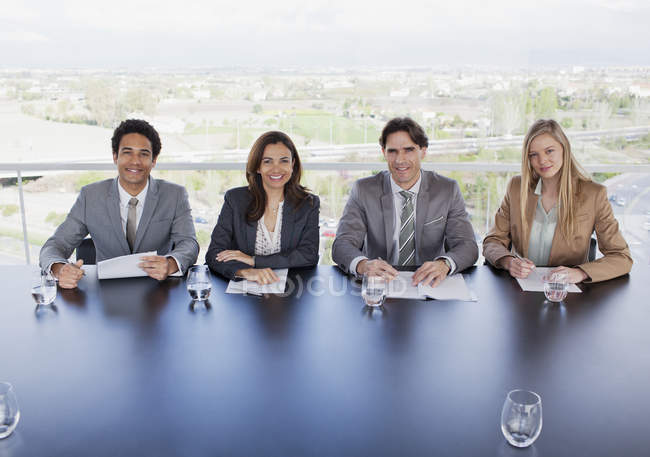 Retrato de gente de negocios sonriente sentada a la mesa en la sala de conferencias - foto de stock