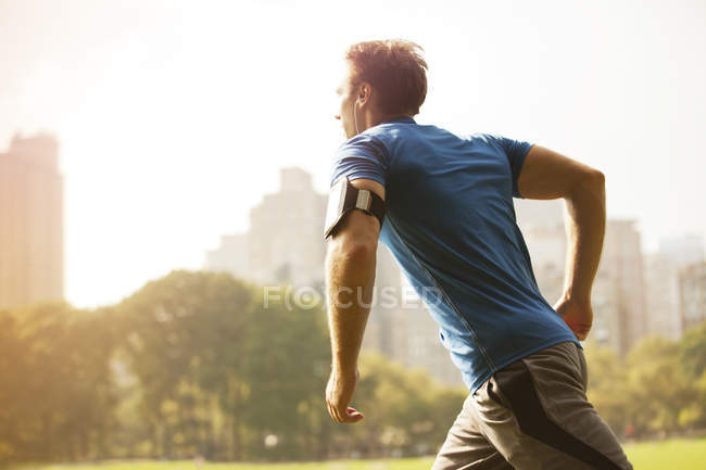 Vista lateral do homem correndo no parque urbano — Fotografia de Stock