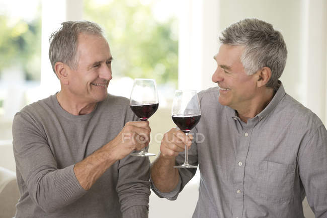 Ältere kaukasische Männer beim Anstoßen auf Weingläser — Stockfoto