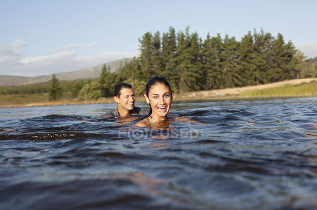 Ritratto di coppia sorridente che nuota nel lago — Foto stock