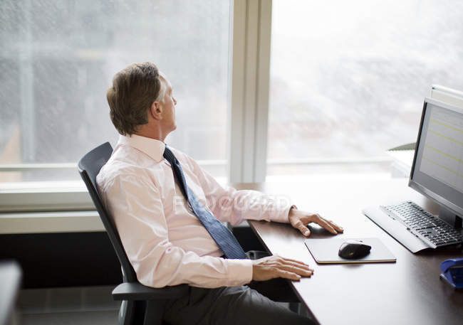 Businessman gazing out window in modern office — Stock Photo
