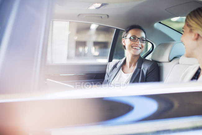 Бізнес-леді розмовляють на задньому сидінні автомобіля — стокове фото