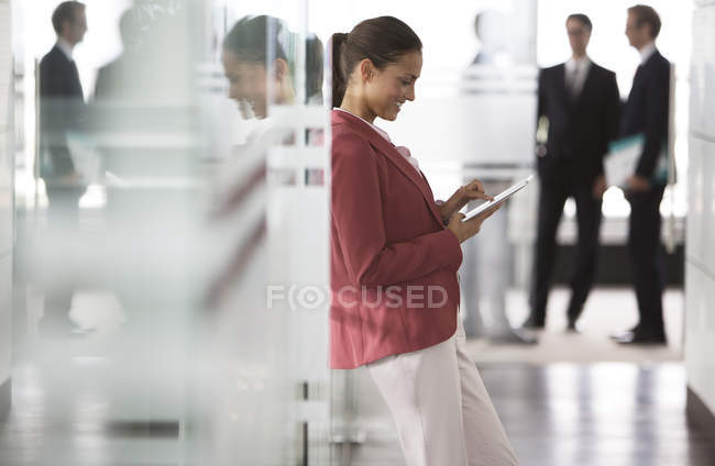 Geschäftsfrau nutzt digitales Tablet auf modernem Büroflur — Stockfoto