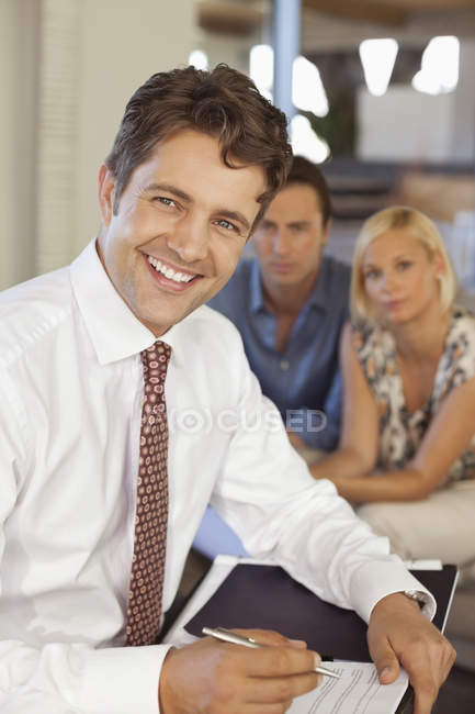 Asesor financiero sonriendo con pareja en sofá - foto de stock