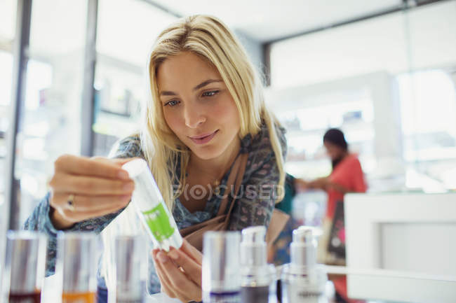 Donna che esamina il prodotto per la cura della pelle in farmacia — Foto stock