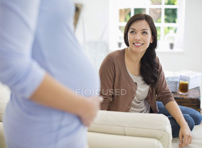 Femme souriant à un ami enceinte — Photo de stock