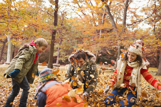Family playing in autumn leaves in park — Stock Photo