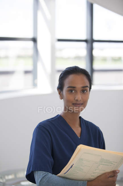 Nurse carrying folder in hospital hallway — Stock Photo