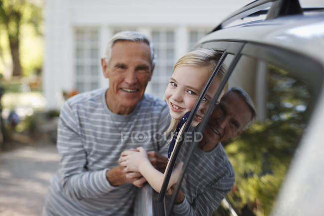 Hombre mayor hablando con su nieta en la ventana del coche - foto de stock
