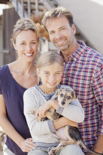Retrato de família sorrindo segurando cachorro — Fotografia de Stock