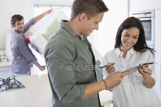 Happy woman signing for delivery in kitchen — Stock Photo