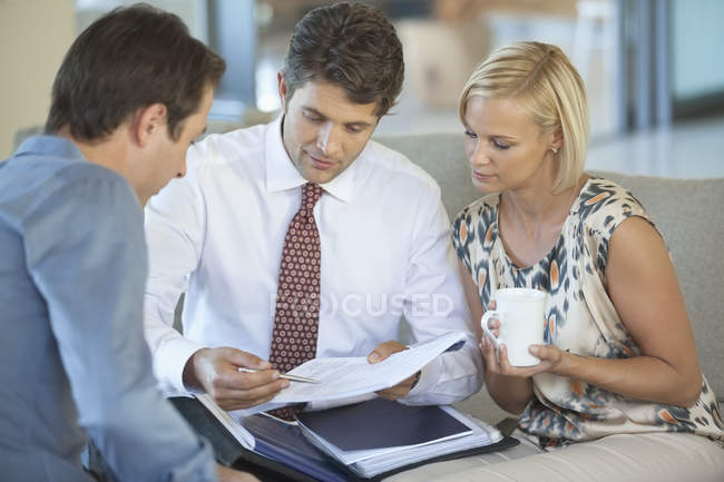 Asesor financiero hablando con pareja en sofá - foto de stock