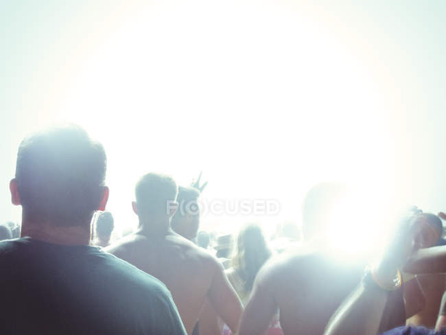 Силуэт вентиляторов, стоящих перед освещенной сценой — стоковое фото