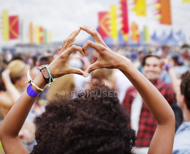 Mujer formando forma de corazón con las manos en el festival de música - foto de stock