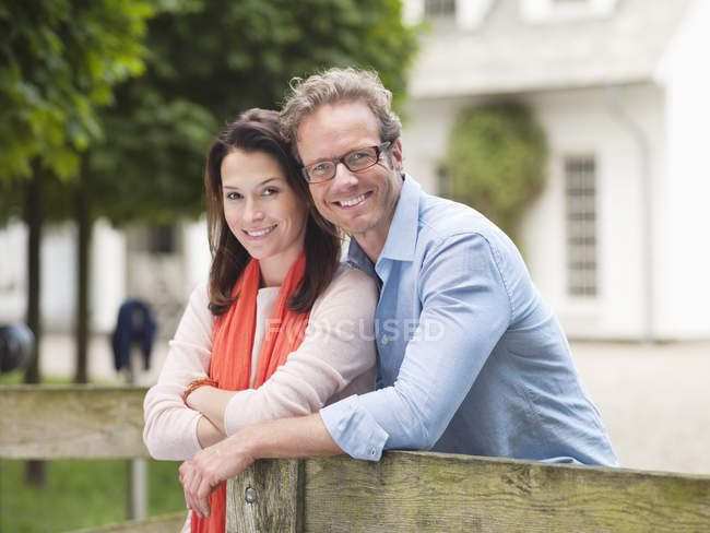 Couple smiling by wooden fence — Stock Photo
