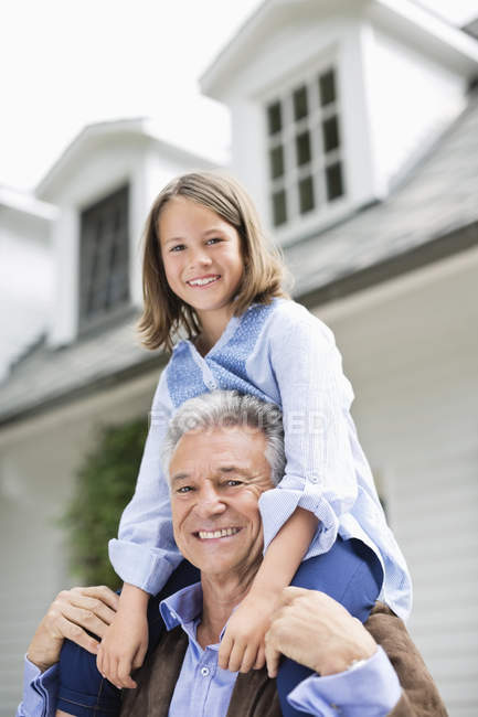 Man carrying granddaughter on shoulder outdoors — Stock Photo