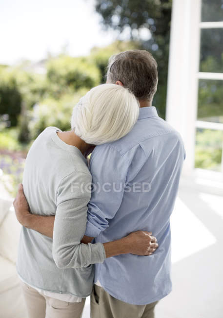 Vista trasera de pareja mayor abrazándose en el patio - foto de stock