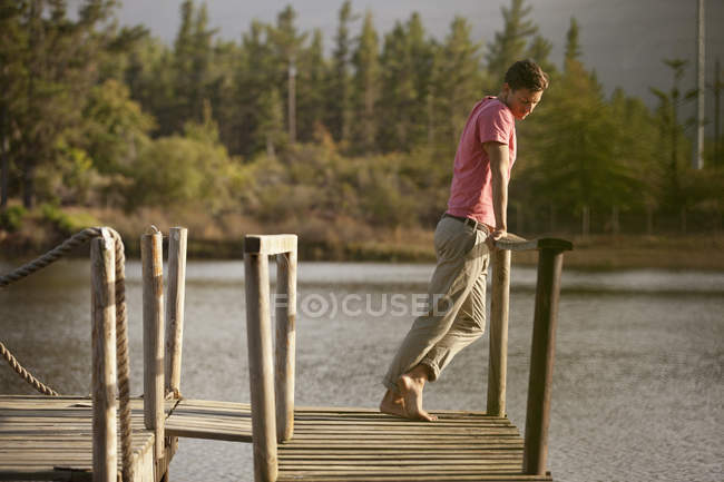 Sereno homem de pé no corrimão da doca sobre o lago — Fotografia de Stock