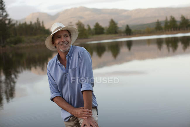 Souriant homme mûr posant au bord du lac — Photo de stock