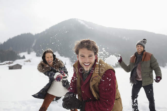 Portrait d'amis ludiques jetant des boules de neige dans le champ — Photo de stock