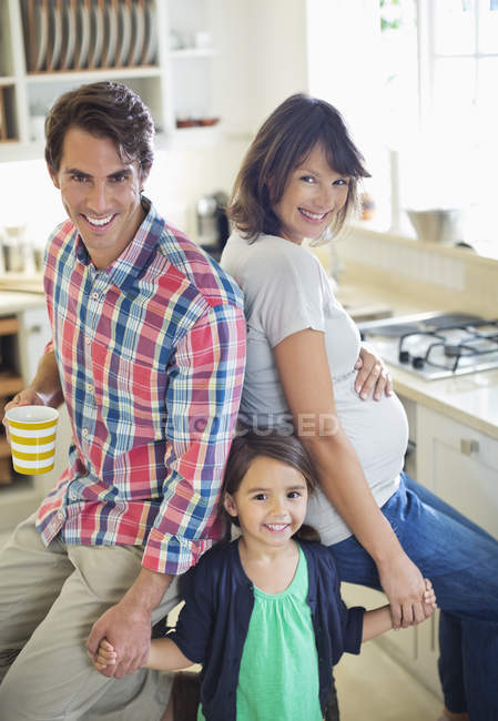 Familia sonriendo juntos en la cocina - foto de stock