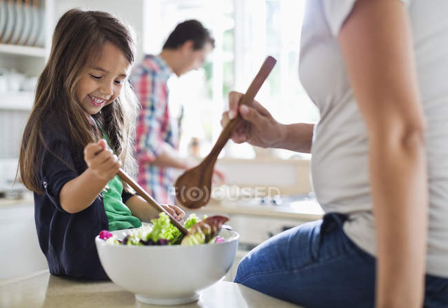 Madre e hija lanzando ensalada juntas - foto de stock