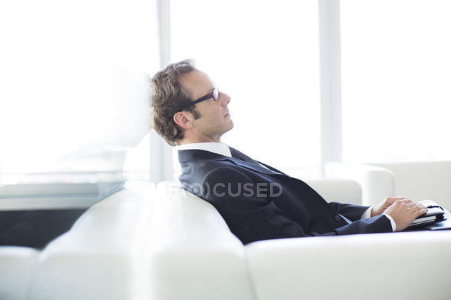 Businessman sitting on sofa in lobby at modern office — Stock Photo