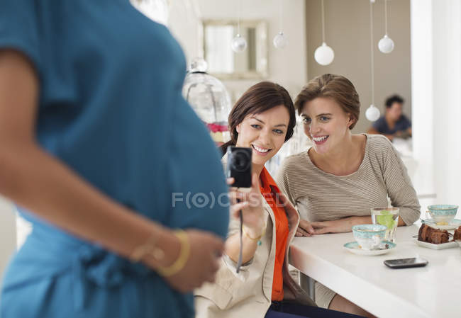 Mujeres tomando fotos de una amiga embarazada - foto de stock