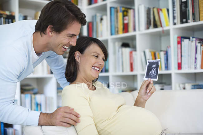 Беременная женщина показывает бойфренду УЗИ — стоковое фото