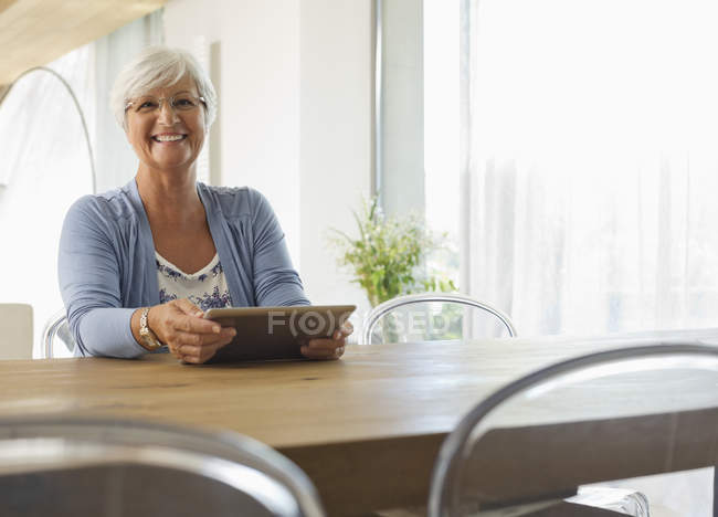 Mulher mais velha usando computador tablet na mesa — Fotografia de Stock