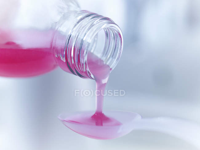Close up of medicine pouring into measuring spoon — Stock Photo