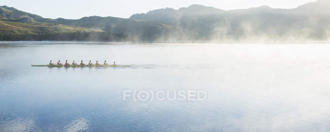 Rowing team rowing scull on lake — Stock Photo