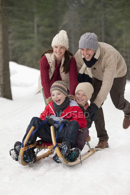 Happy family sledding in snowy woods — Stock Photo
