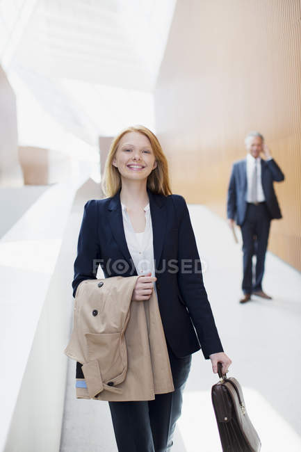 Porträt einer lächelnden Geschäftsfrau mit Mantel und Aktentasche — Stockfoto