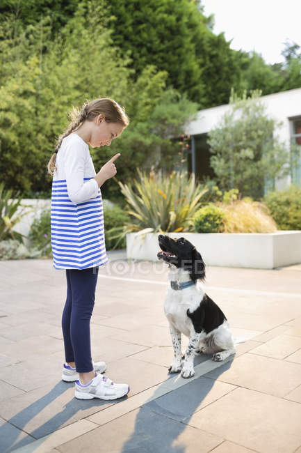 Side view of girl scolding dog outdoors — Stock Photo
