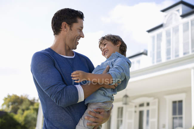 Pai e filho sorrindo fora da casa — Fotografia de Stock