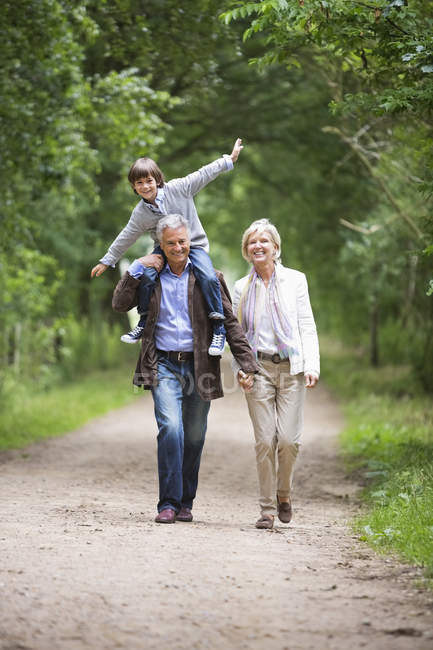 Пара прогулок с внуком по сельской дороге — стоковое фото