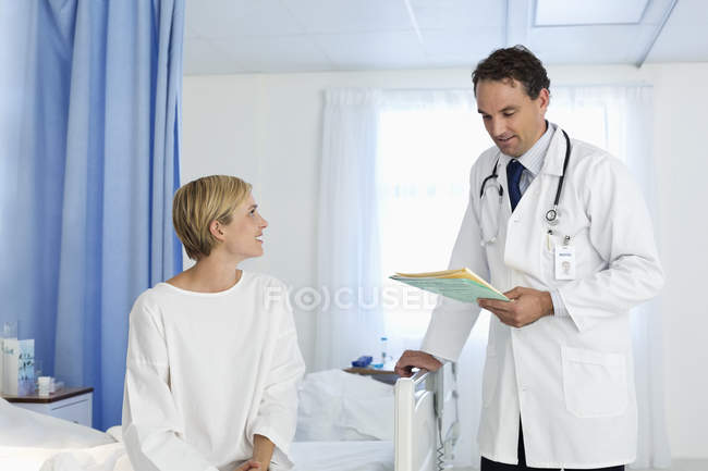Doctor hablando con el paciente en la habitación del hospital - foto de stock