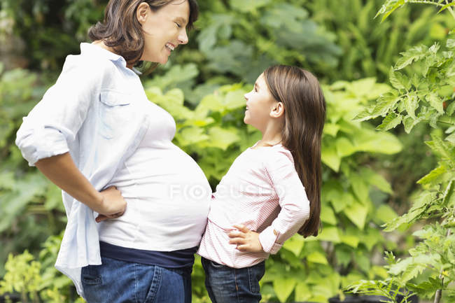 Girl bumping pregnant mothers belly — Stock Photo