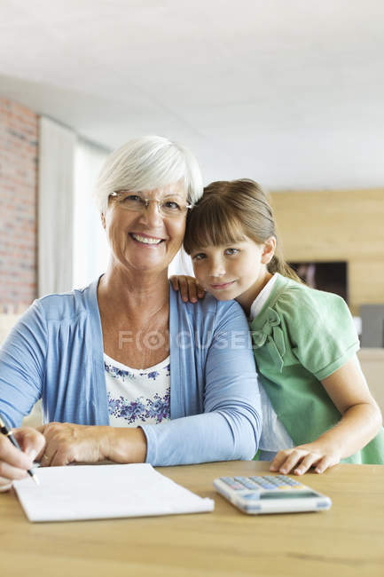 Пожилая женщина и внучка с помощью калькулятора — стоковое фото